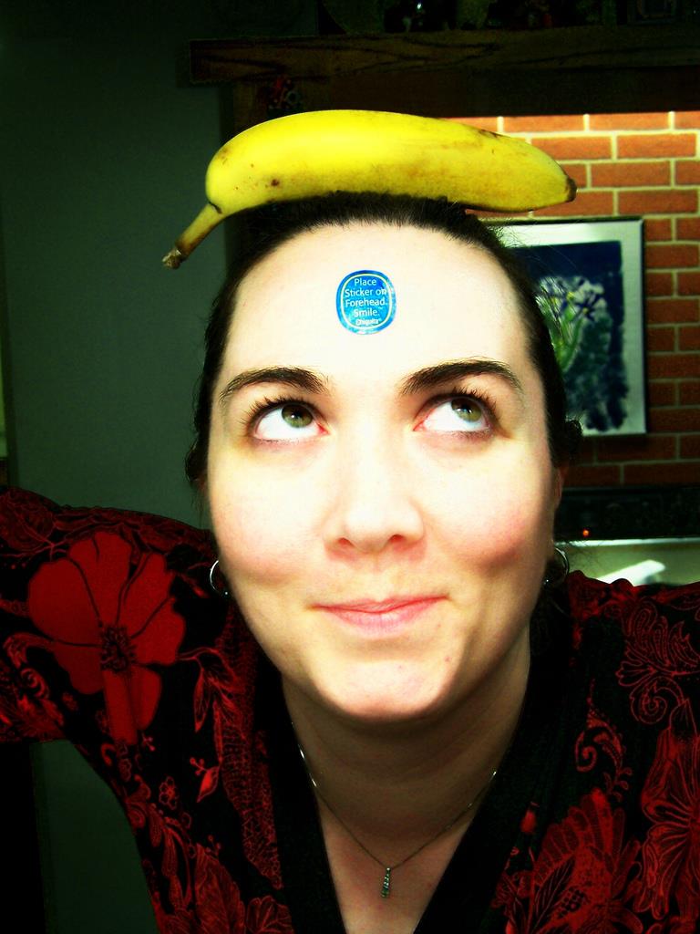 A woman smiling with a banana on her head.